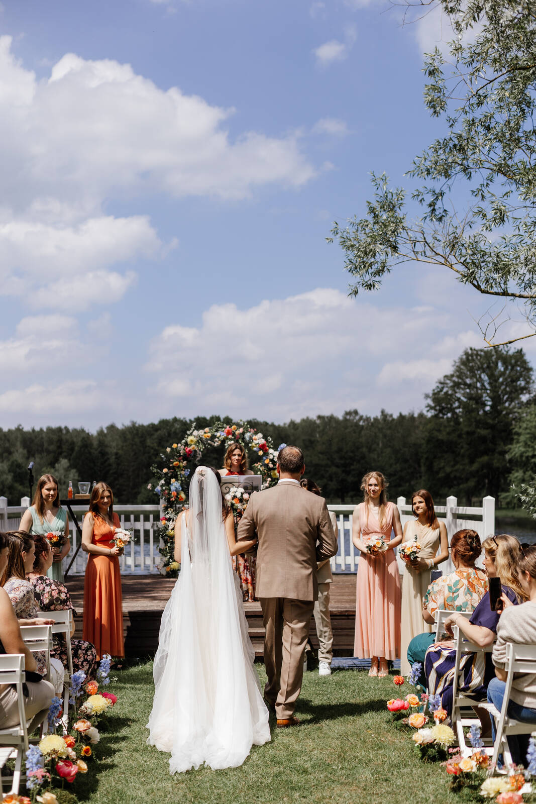 Cérémonie de mariage en plein air, arche fleurie et invités sous un grand ciel bleu