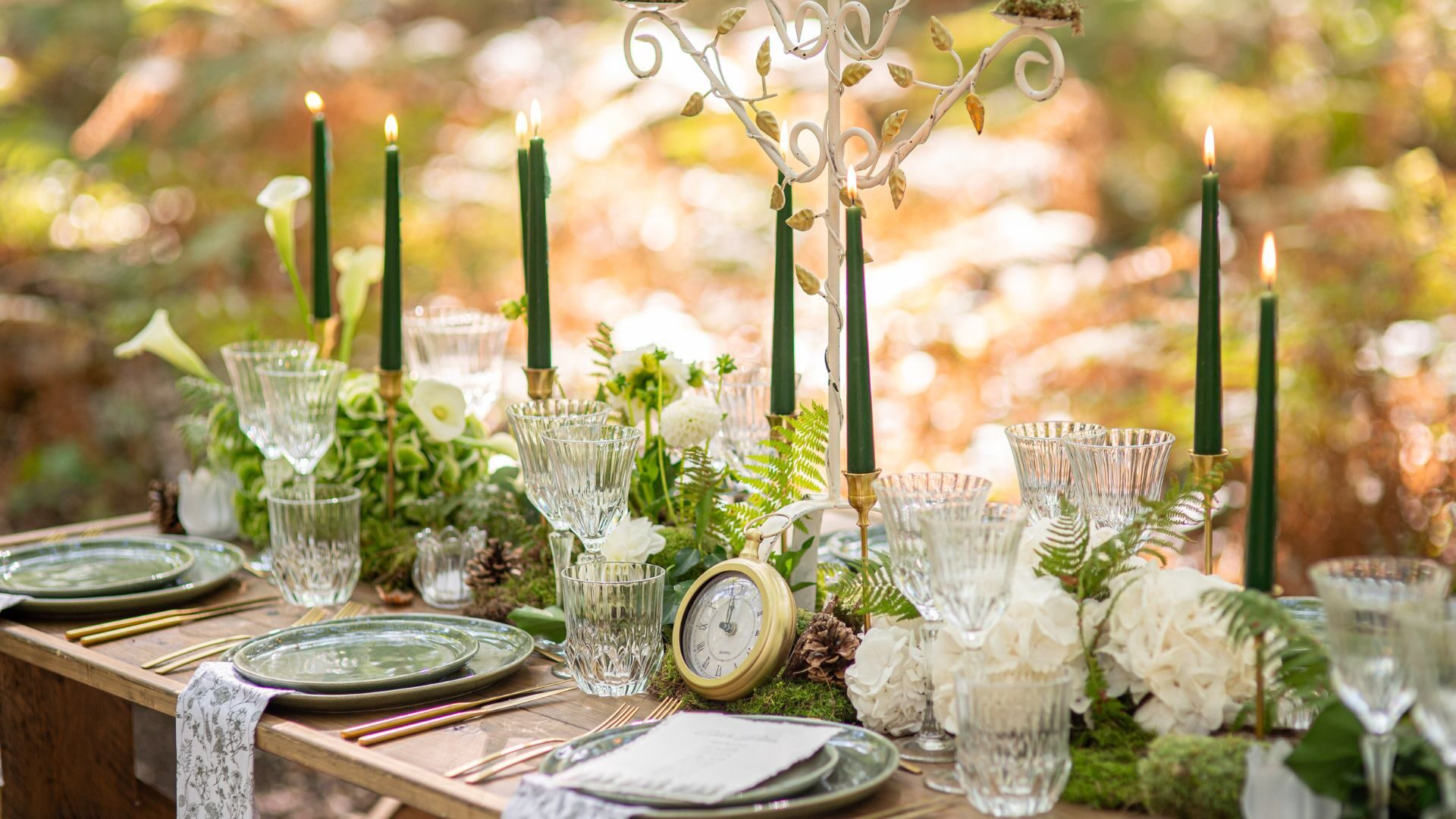 Table dressée avec bougies vert sapin, verrerie ancienne et horloge de poche