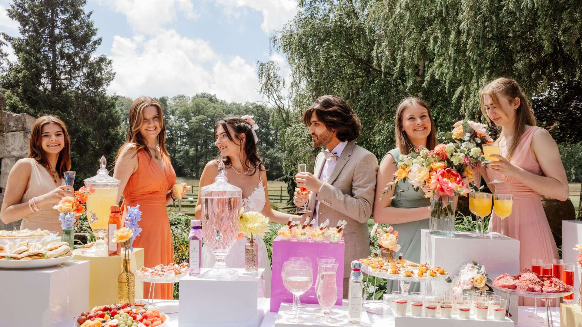 Invités réunis autour d'un buffet de réception fleuri, mariage en plein air