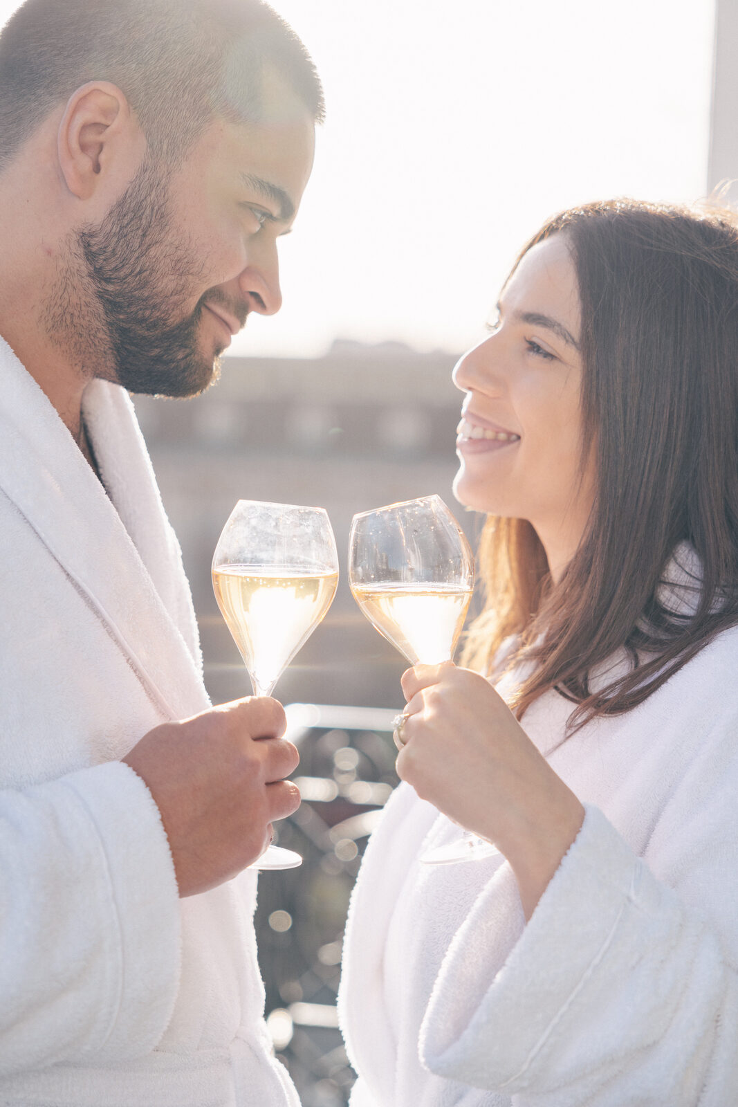 Couple en peignoir blanc trinquant au champagne, préparatifs avant une demande en mariage