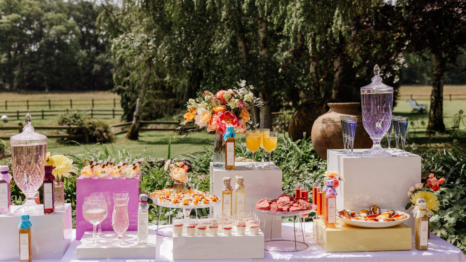Table extérieure dressée avec boissons et douceurs sucrées dans un jardin fleuri