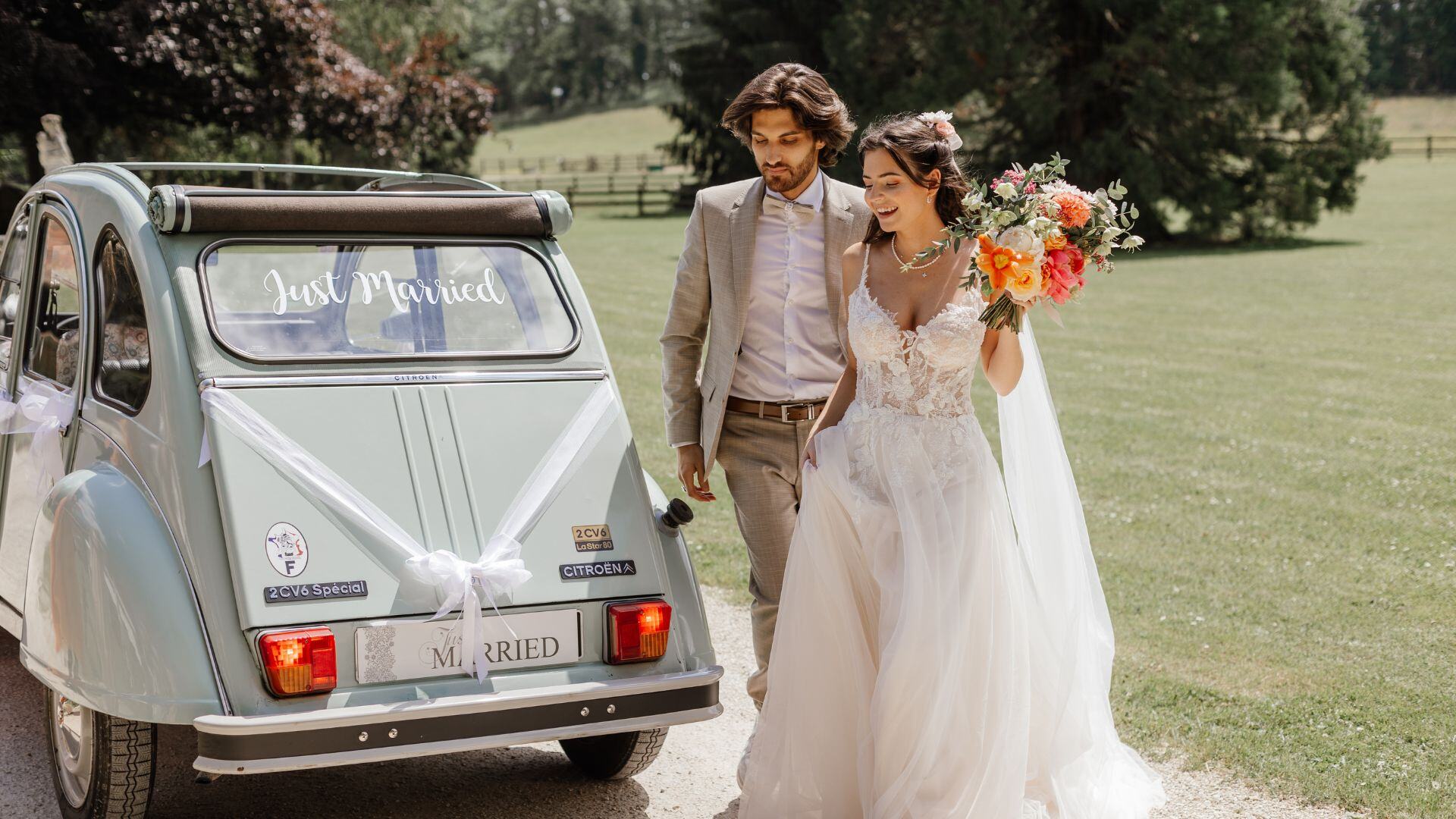 Mariés marchant devant une 2CV décorée « Just Married », organisé par Oréa Events