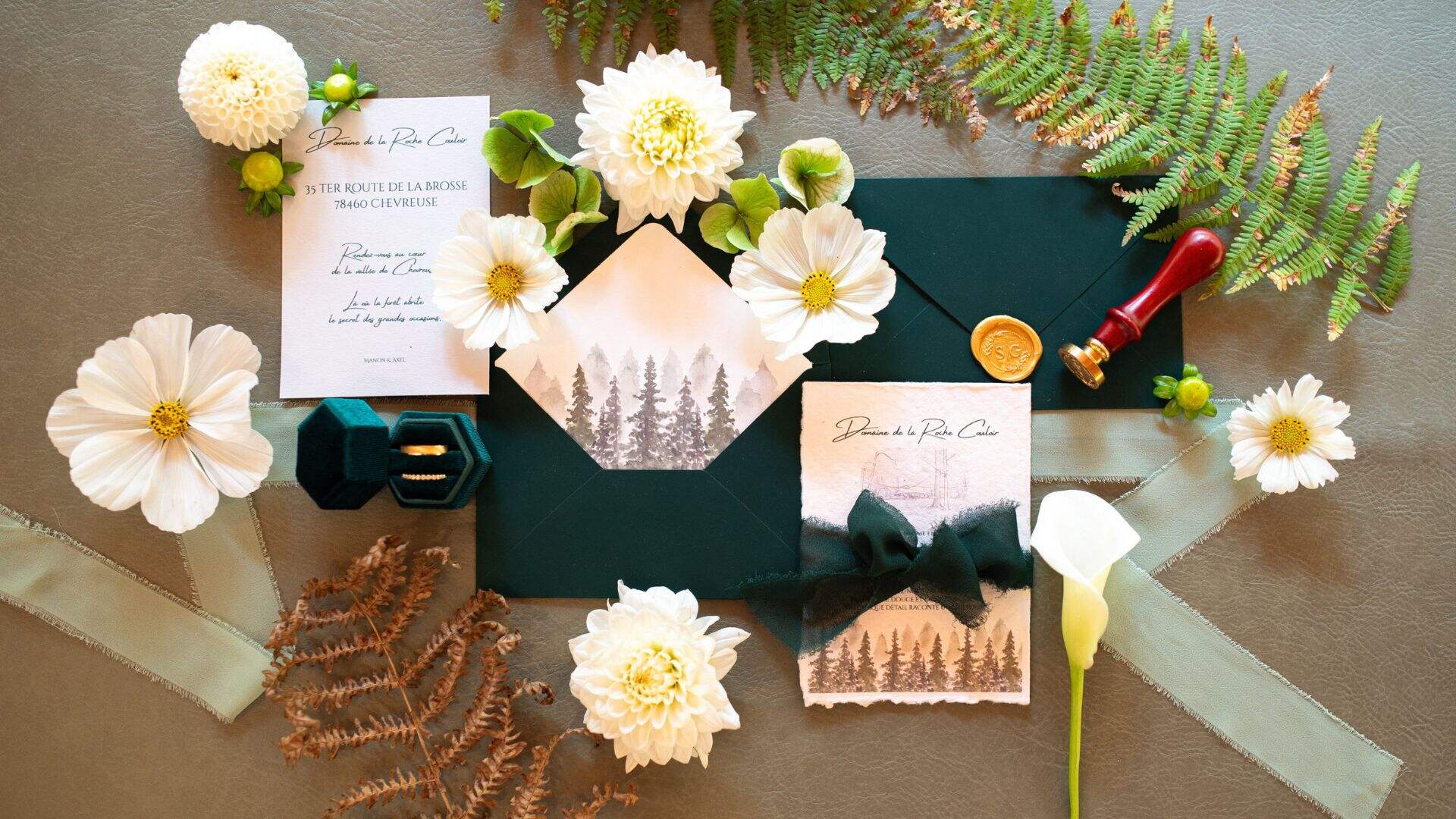 Faire-part de mariage vert sapin, fleurs fraîches et cachet de cire sur papier ivoire à bords irréguliers